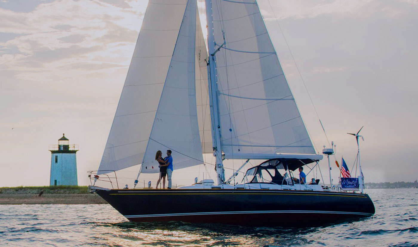 Far away photo of sailboat with a couple embracing on the bow of boat